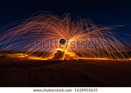 Steel wool fire spark on the top of the desert rock at the night time with slow shutter speed technique