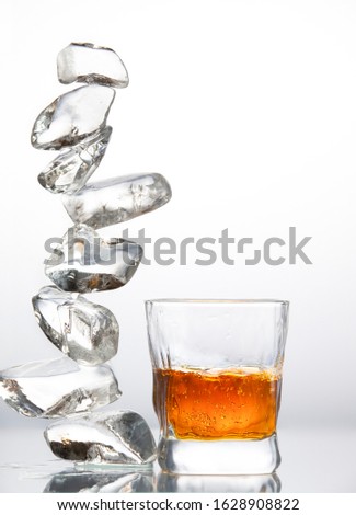 A low transparent glass with alcohol and pieces of ice folded in a column