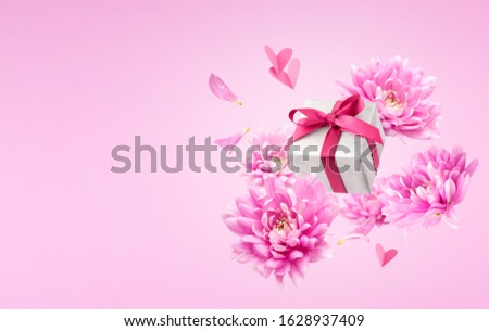 Pink flowers, gift, paper hearts and petals fly or fall. Magic concept. Romantic background for Valentine Day, Mothers or Womans Day.