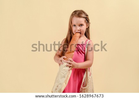 happy girl in a pink dress with bread. In the studio on a light background. healthy nutrition, organic foods. Kraft bread and bag bag.
