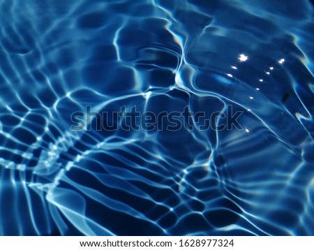 The abstract​ of surface​ blue​ water​ for​ background. The​ pattern​ of​ metal​ texture​ on​ blue​ water​ for​ background​