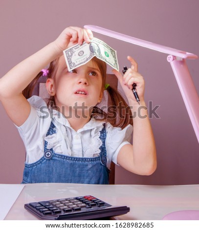 Banking and financial security concept. Humorous portrait of cute little business child girl checking US Dollar banknote for watermark. 