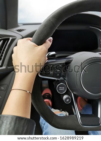 Woman hand holding a sport car steering wheel