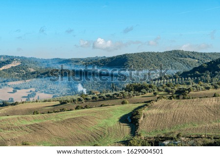 Beautiful foggy landscape in Tuscany - wave hills, green grass and morning fog. ItalyTuscany landscape on the hills