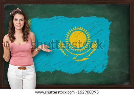 Beautiful and smiling woman showing flag of Kazakhstan on blackboard, presentation for tourism and marketing research