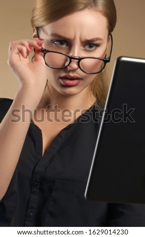 Confused girl taking off eye glasses and looking at the tablet