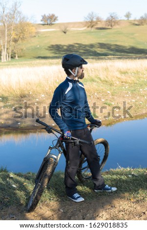 Cyclist in pants and fleece jacket on a modern carbon hardtail bike with an air suspension fork rides off-road.