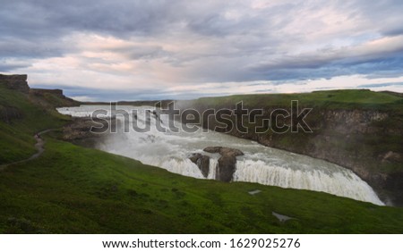 a picture of the impressive and gigantic waterfall gulfoss in iceland, taken during the blue hour on a cloudy day.