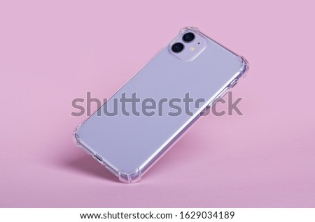 Purple iPhone 11 in clear silicone case falls down isolated on pink background. Phone case mockup back view
