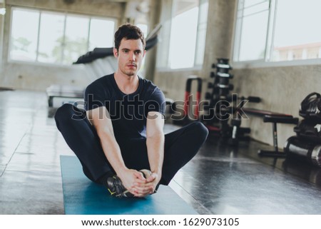 Athletic men stretching before exercising on yoga mats in the gym.