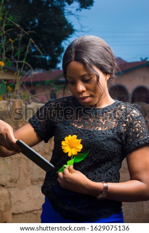 young black woman holding a flower checks her mobile phone