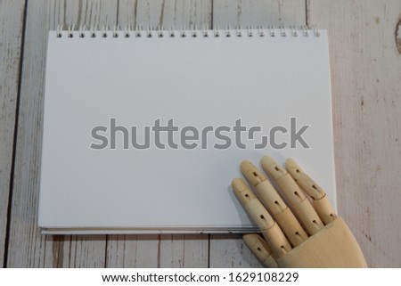 wooden hand write on white paper and holding pen. 