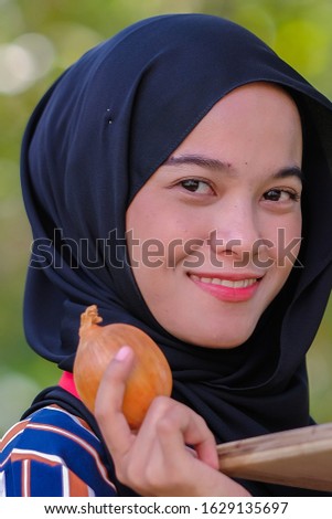 Close up headshot of pretty female holding an onion in the garden