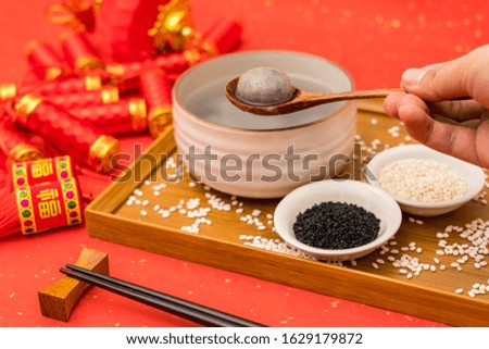 Chinese Lantern Festival traditional food black sesame dumplings on red background with Chinese word in the picture means "good luck"
