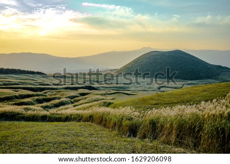 Komezuka or Mt. Kishima of Mount Aso or Aso-san from Kusasenri Observatory area. Mt.Aso with grass along into the mount on background of sunset Royalty-Free Stock Photo #1629206098