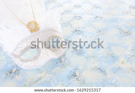Photo of elegant and delicate white Venetian mask over pastel wooden background