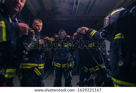 Group of firefighters standing inside the fire brigade wearing helmet and protective uniform