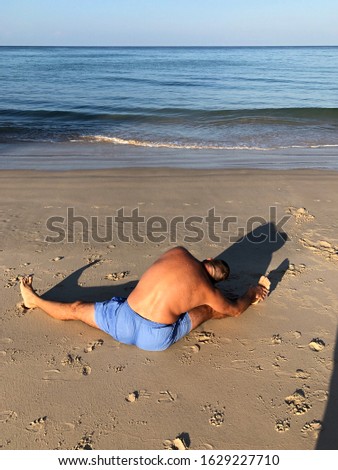 a man goes in for sports, does exercises, trains on the beach by the ocean