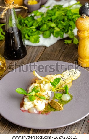 rustic wooden background, top and side, on a plate, halibut fish appetizer, olive tapenade, croutons, greens and vegetables