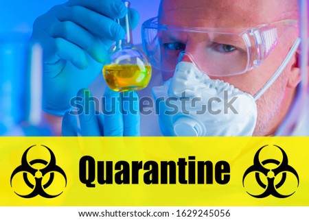 A scientist holds a test tube. The inscription quarantine and the international biohazard sign. The concept of fighting viruses. Bacteriology. Virology. Scientific research.