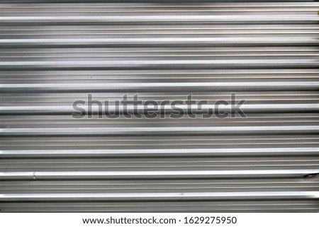 silver metal door of a garage with horizontal relief lines reflecting the light
