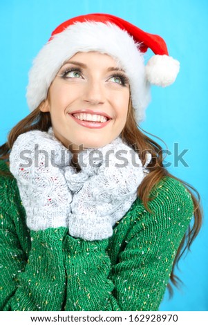 Beautiful smiling girl in New Year hat on blue background