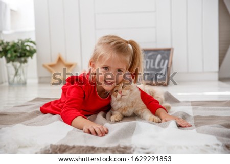 a little girl with a mankun kitten lying on the floor of the house. The concept of a human family and a pet