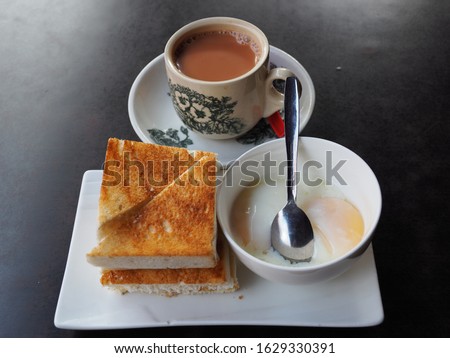 Singapore Breakfast called Kaya Toast, Coffee bread and Half-boiled eggs, Chinese coffee in vintage mug and bread toast with a local jam made from eggs, sugar and coconut milk Royalty-Free Stock Photo #1629330391