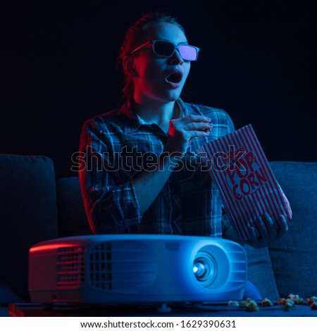 Cheerful viewing of a girl in 3D glasses at a home theater. Rest and relaxation. Square photo.
