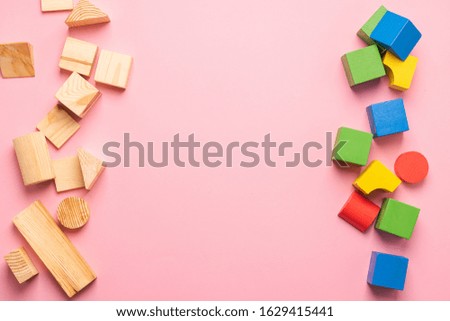 Children's wooden toys on a pink background concept zero west. Frame from developing colored cubes. Copy space. Top view