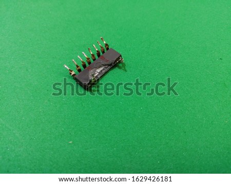 Old damaged microcircuit with a pin on a green background