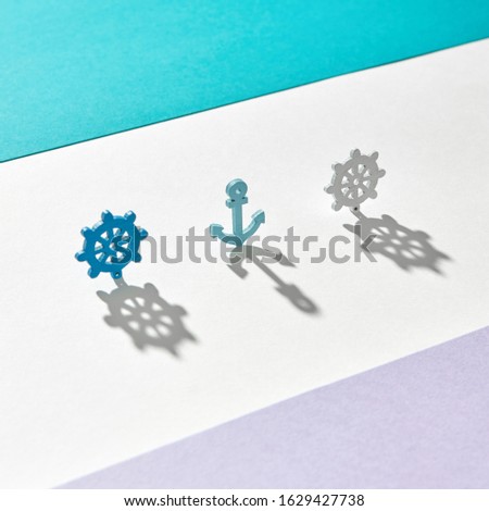 Marine pattern from anchor and wheels with long hard shadows on a tricolor background with copy space.