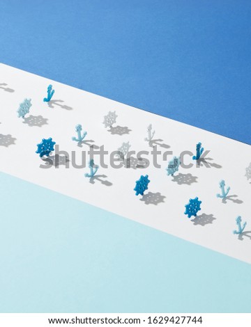Wide white lane with plastic toys of marine wheels and anchors shadows on a light blue background, copy space.