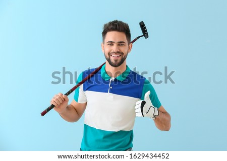 Handsome male golfer showing thumb-up on color background