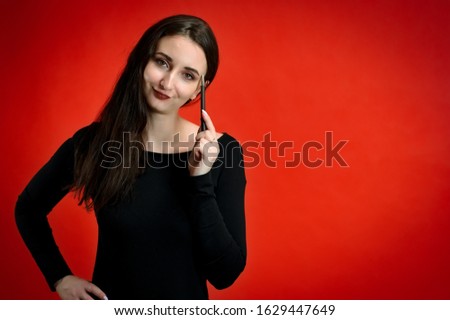 Photo of a pretty young brunette woman with a smile with good makeup on a red background. Concept girl talking in front of the camera with emotions.