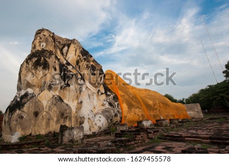 Stone statue Big Buddha wears yellow fabric recline outdoor at Ayudhaya history park