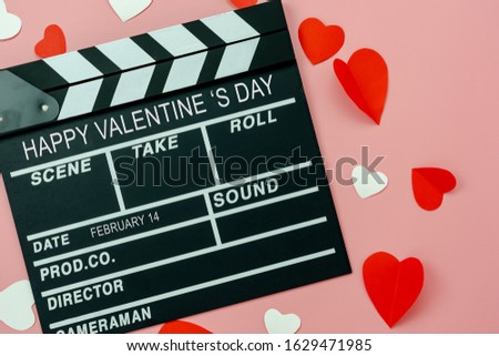 Table top view aerial image of decoration valentine's day background concept.Flat lay essential items colorful love shape paper cut with welcome word on movie clapper with modern pink wallpaper.