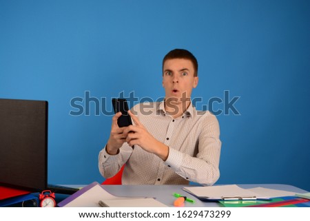 business man surprised in hand smartphone on blue background