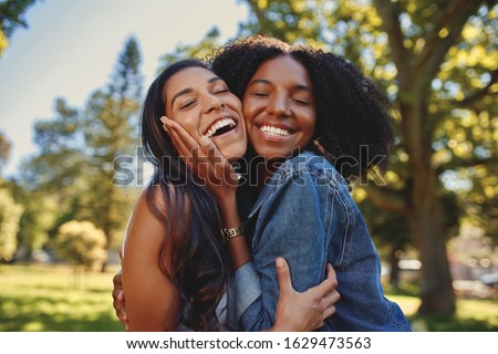 Close up lifestyle portrait of diverse multiracial happy best friends hugging each other and laughing in the park Royalty-Free Stock Photo #1629473563