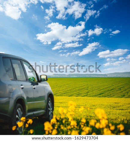 Car parked in a green field on a country road. Beautiful spring day at countryside. Location place of Ukraine, Europe. Scenic image of agrarian industry. Photo of ecology concept. Beauty of earth.