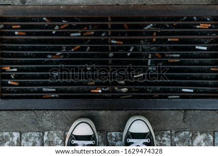 Garbage on the street. Cigarette butts. Top view on shoes. Royalty-Free Stock Photo #1629474328