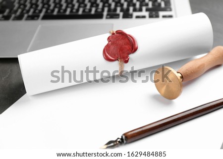 Notary's public pen and sealed document near laptop on grey stone table