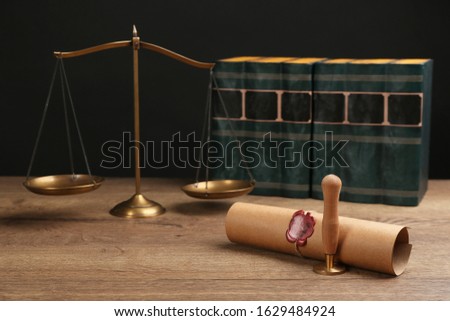 Notary's public pen, sealed document and scales on wooden table