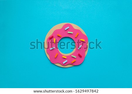 Handmade paper art strawberry donuts with colorful sprincles on blue paper background. Paper cutting, 3d illustration.  