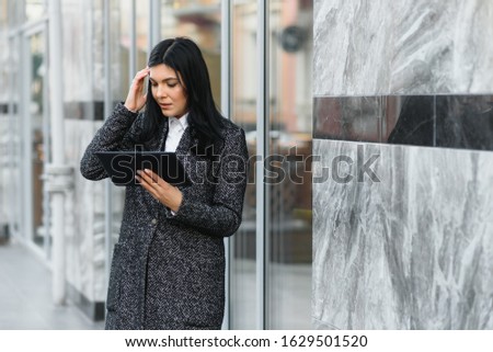 Businesswoman working on digital tablet outdoor over building background
