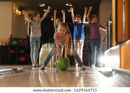 Girl throwing ball and spending time with friends in bowling club