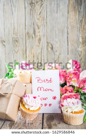 Happy moms day greeting background. Mothers day sweet cupcakes, with gift boxes, coffee cappuccino cup, flowers. Wooden background copy space