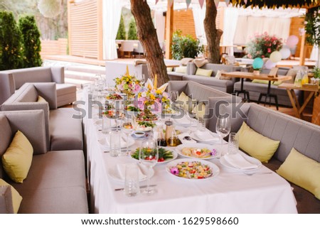 Festive food on the table at the restaurant. Stylish decoration of the table with flowers in a vase and a candle.