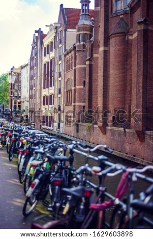Vertical picture of old brown bricky dutch buildings in Amsterdam, Netherlands with a lot of bicycles in front of them. Typical holland house near canal. Amsterdam famous touristic destination