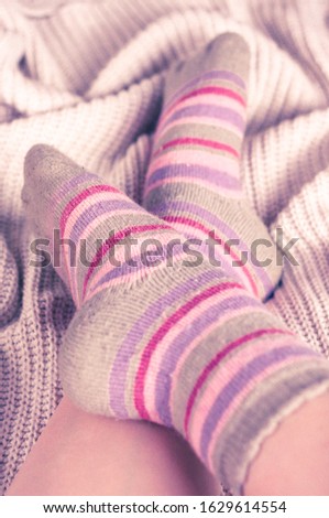 Feet in striped woolen socks on knitted backdrop